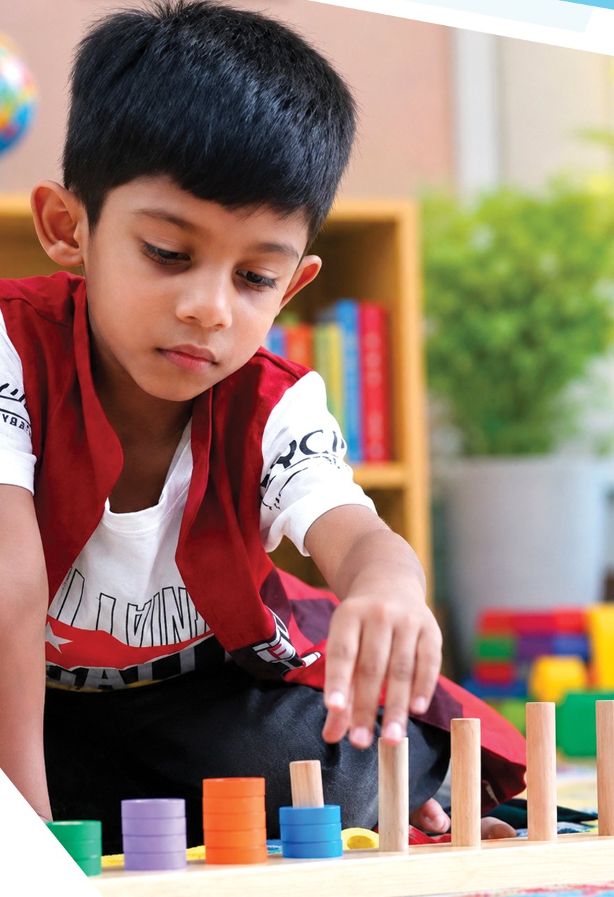 A young child happily learning with colourful counting toys at Shriyam Pre School
